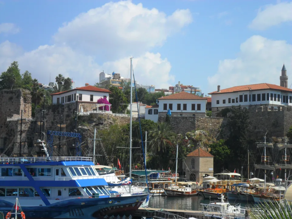 Regional Antalya city context: moored boats beneath the cliffs and buildings of Kaleiçi harbour.