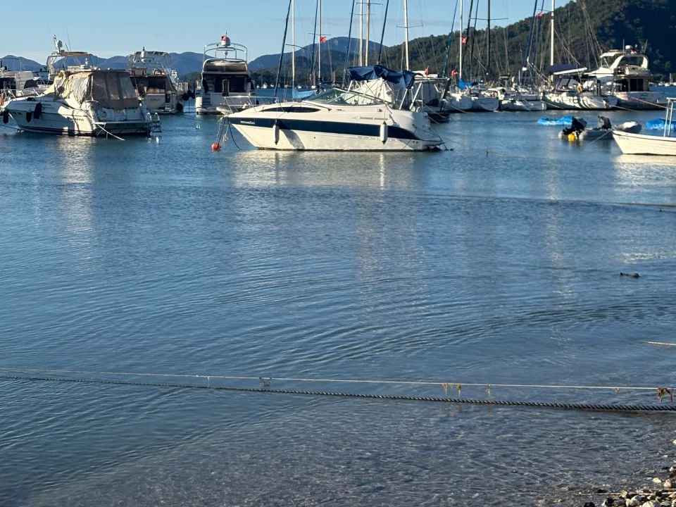 Sailing yachts and masts beside the Göcek waterfront.