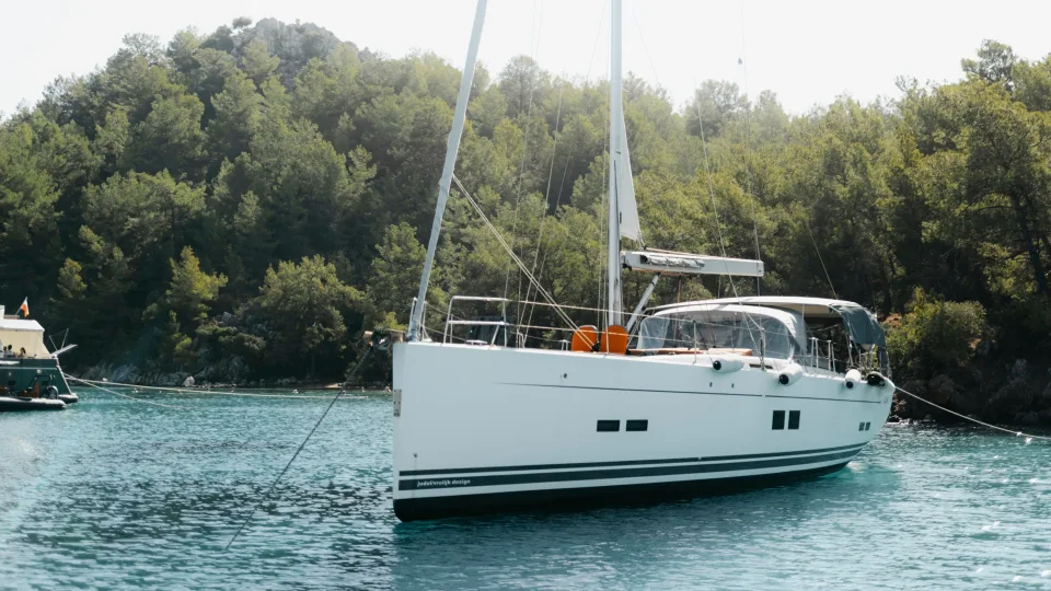 A white sailing yacht beside the treed coast at Selimiye.