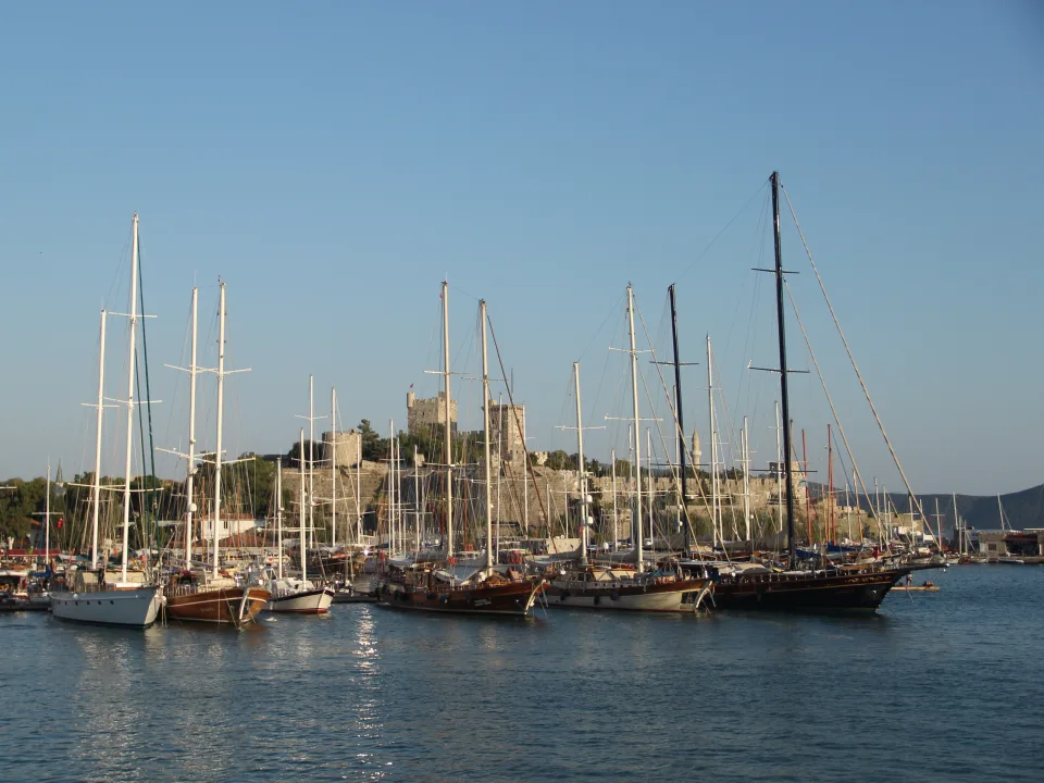 Wooden sailing vessels and their masts beneath Bodrum Castle.